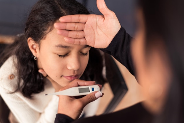 Niña con síntomas de coronavirus tiene dolor de garganta Madre revisa su temperatura