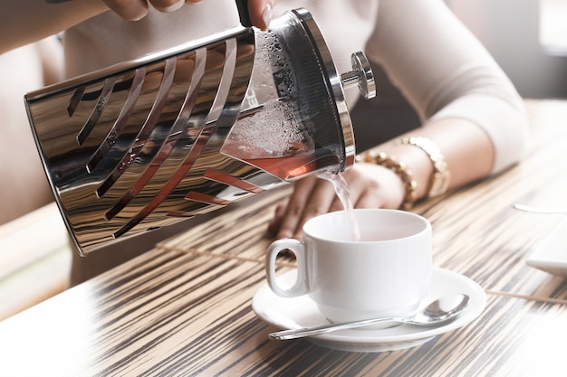 La niña sirve té en una taza de la prensa francesa Light.