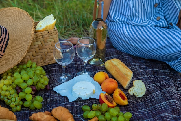 La niña sirve vino en un picnic. Enfoque selectivo. Naturaleza.