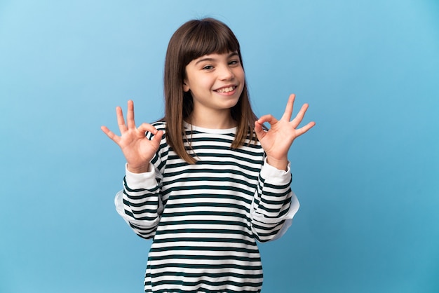 Niña sobre fondo aislado mostrando el signo de ok con las dos manos