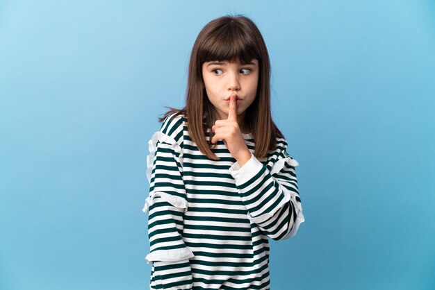 Niña sobre fondo aislado mostrando un signo de silencio gesto poniendo el dedo en la boca