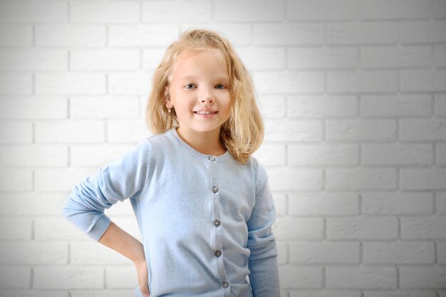 Niña sobre un fondo de pared de ladrillo blanco