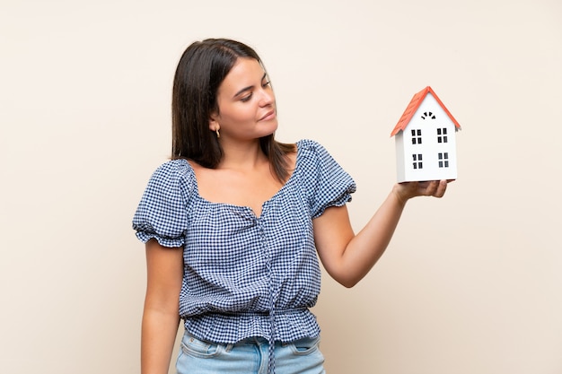 Niña sobre pared aislada sosteniendo una casita