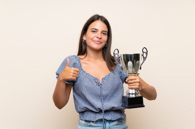 Foto niña sobre pared aislada sosteniendo un trofeo