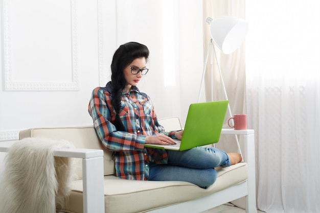 Niña en el sofá blanco con una computadora portátil