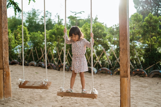 Una niña sola en el columpio de madera