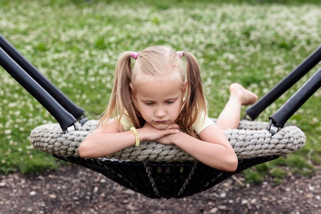 Niña solitaria Niña sola en el columpio Infeliz Estresado Triste Molesto Aburrido Niño en la naturaleza Problemas de los niños