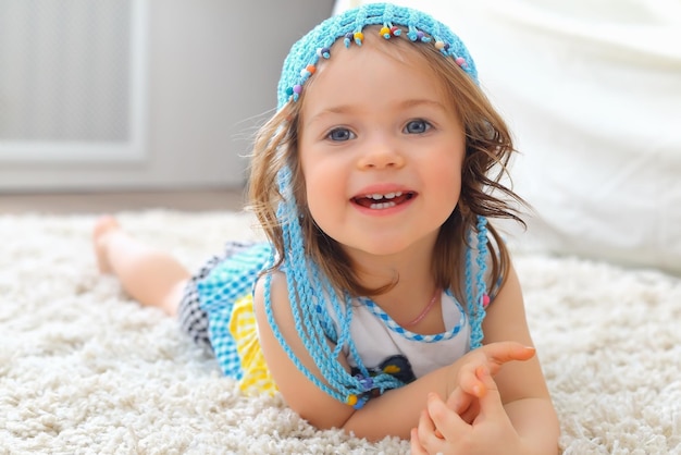 Niña sombrero azul alfombra blanca