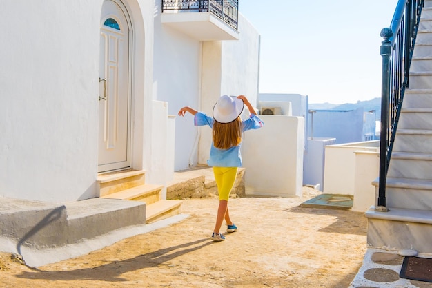 Niña con sombrero blanco pasando vacaciones en una calle de Grecia Mykonos