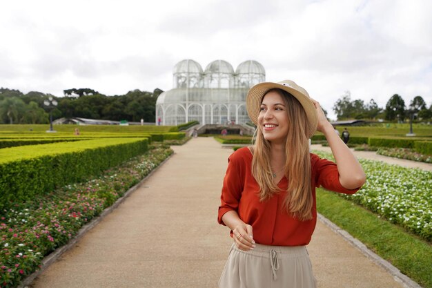 Foto niña con sombrero caminando mirando hacia el lado en el jardín botánico de curitiba parana brasil