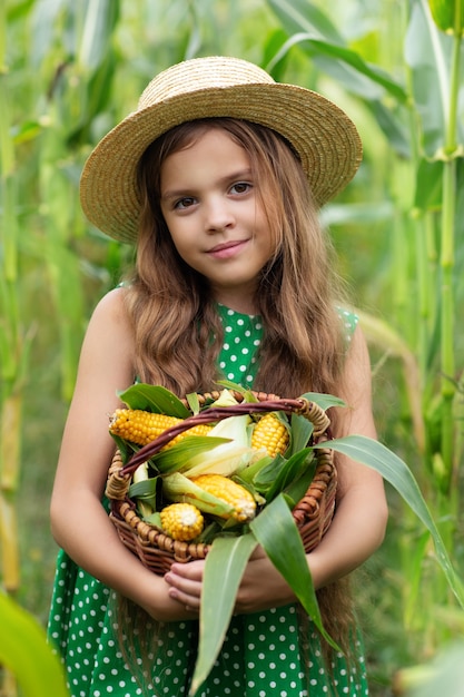 Foto niña, en, un, sombrero, con, un, canasta de maíz