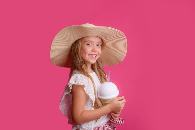 niña con un sombrero de color rosa con un cóctel refrescante.