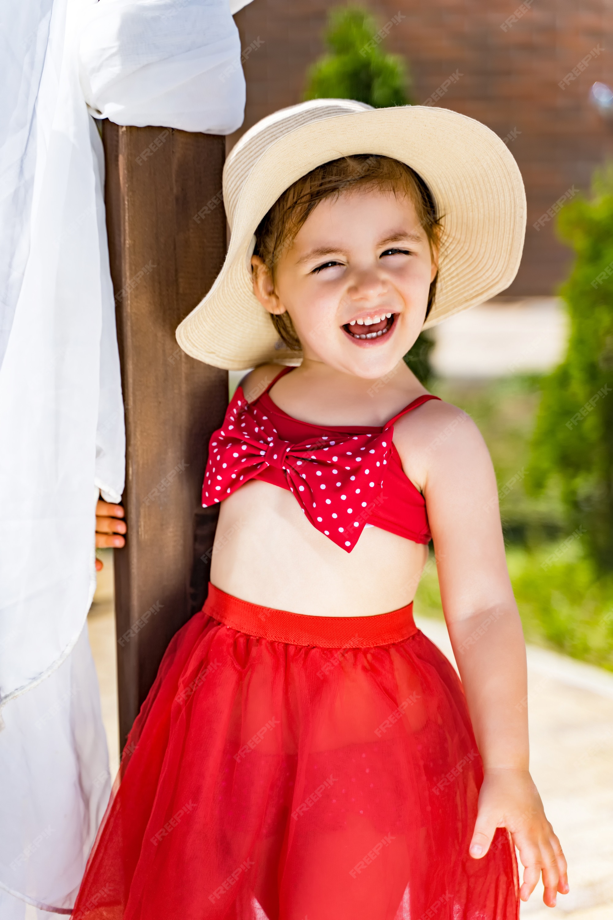 Niña en un sombrero y una falda en playa se ríe Foto Premium