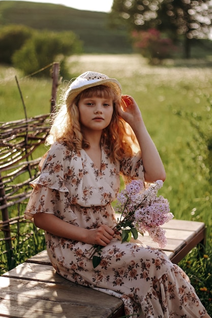 Niña con un sombrero con flores en el parque de verano