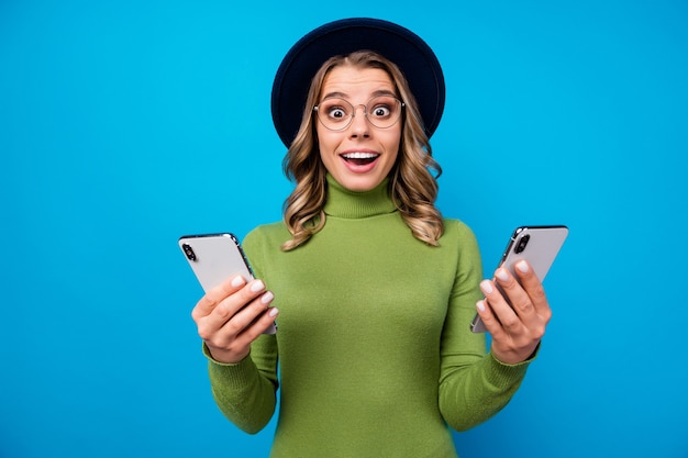 niña con sombrero y gafas sosteniendo teléfonos