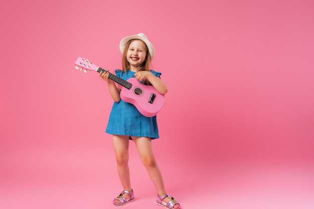 Niña con sombrero y una guitarra de ukelele