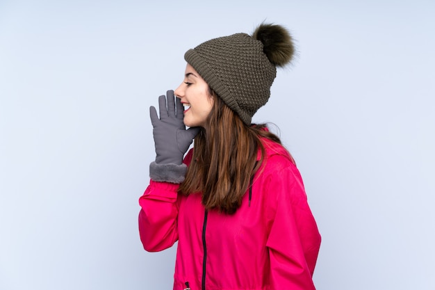 Niña con sombrero de invierno aislado en azul