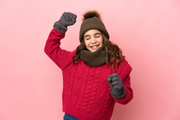 Niña con sombrero de invierno aislado celebrando una victoria