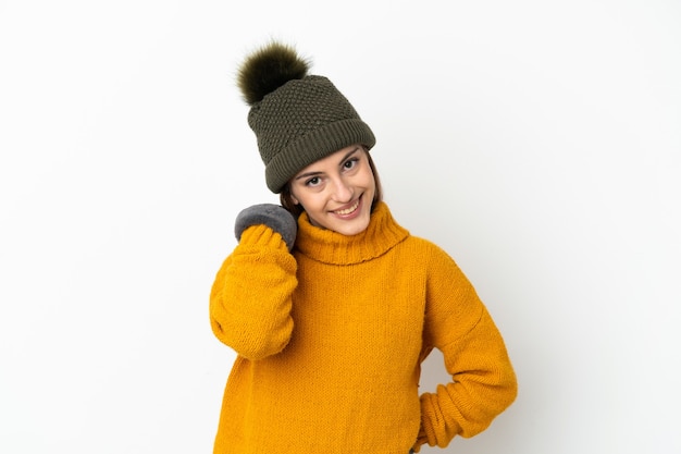 Niña con sombrero de invierno aislado sobre fondo blanco riendo