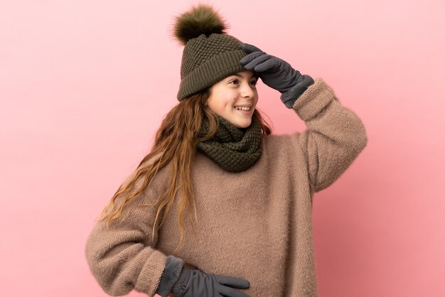 Foto niña con sombrero de invierno aislado sobre fondo rosa sonriendo mucho