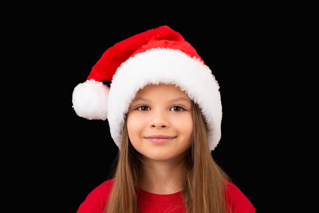 Niña en un sombrero de Navidad posando.