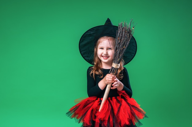 Niña con sombrero negro y disfraz de bruja con escoba