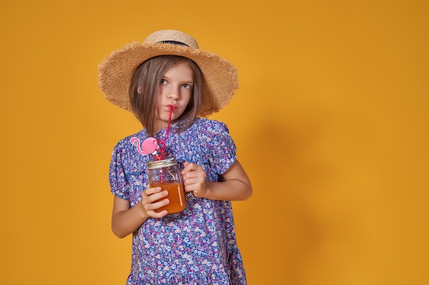 La niña con un sombrero de paja y gafas de sol está sonriendo sobre un fondo amarillo Niña con un vestido azul ...