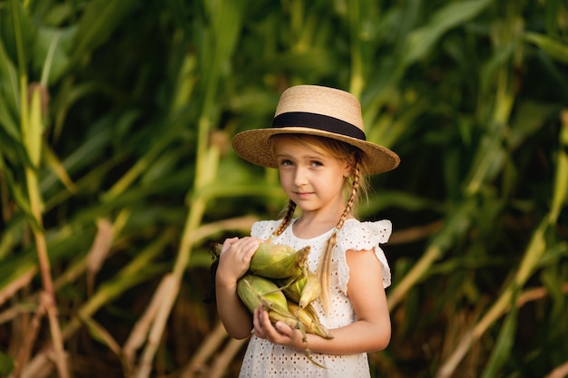 Niña con sombrero de paja con mazorcas de maíz