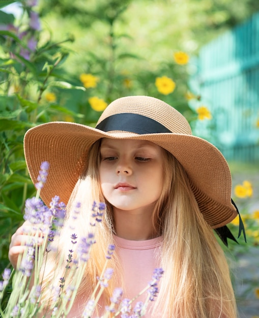 Niña con sombrero de paja rodeado de flores de lavanda