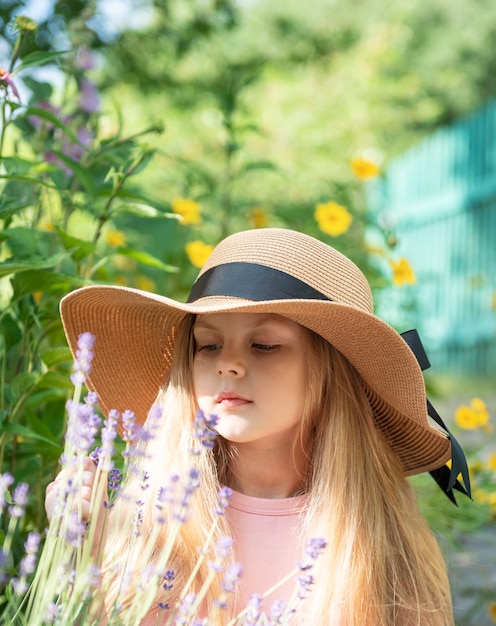 Niña con sombrero de paja rodeado de flores de lavanda