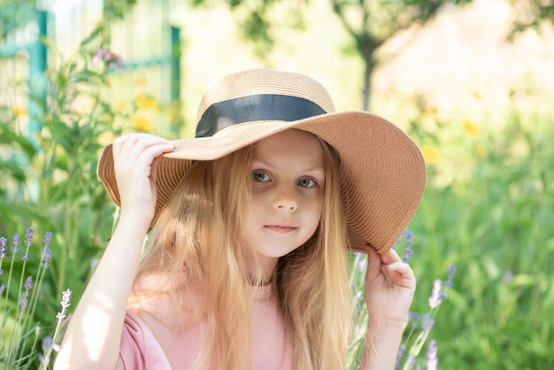 Niña con sombrero de paja rodeado de flores de lavanda