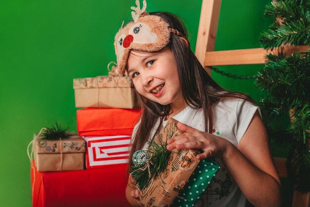 Una niña con un sombrero de Papá Noel se divierte sobre un fondo verde