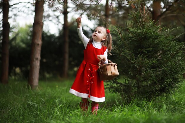 Una niña con un sombrero rojo y vestidos está caminando en el parque. Cosplay para el héroe de cuento de hadas "Caperucita Roja"