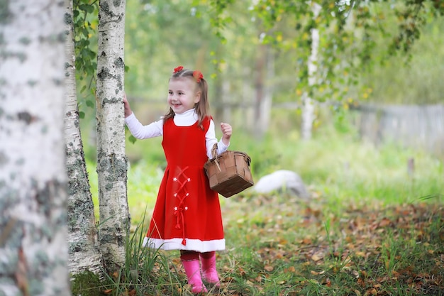 Una niña con un sombrero rojo y vestidos está caminando en el parque Cosplay para el héroe de cuento de hadas Caperucita Roja