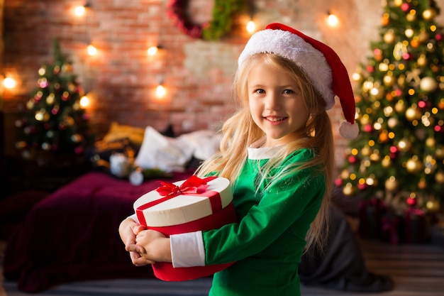 Niña con sombrero de Santa con una caja de regalo