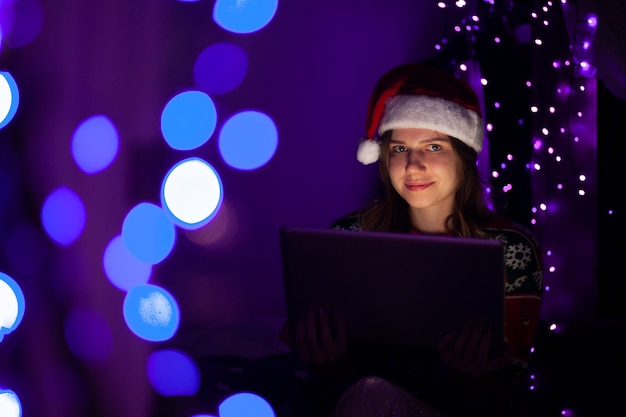 Niña con un sombrero de Santa Claus con una computadora portátil