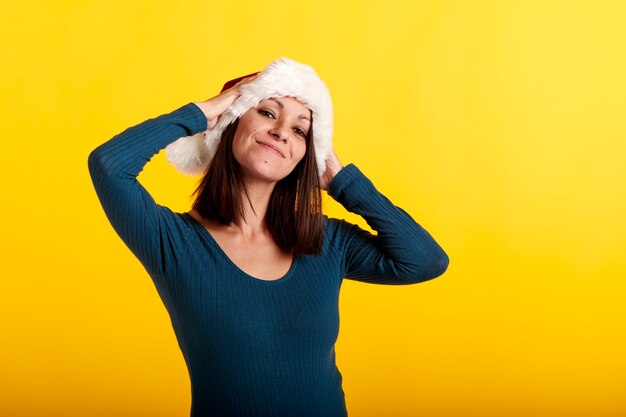 Una niña con un sombrero de Santa Claus con un fondo amarillo