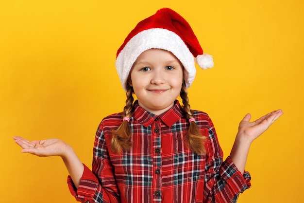 Niña con sombrero de santa se encoge de hombros.