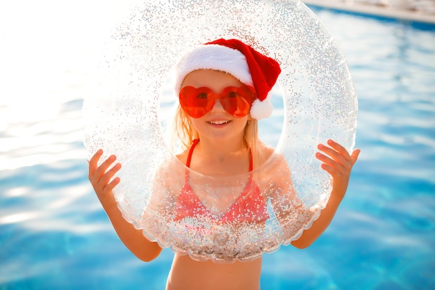 niña con sombrero de Santa en verano en la piscina