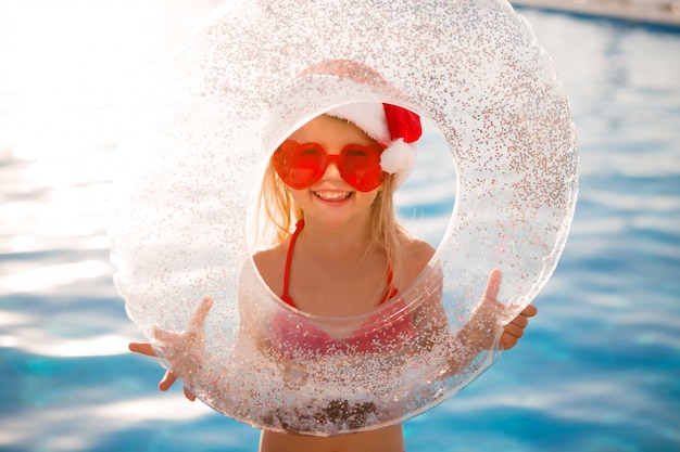 niña con sombrero de Santa en verano en la piscina