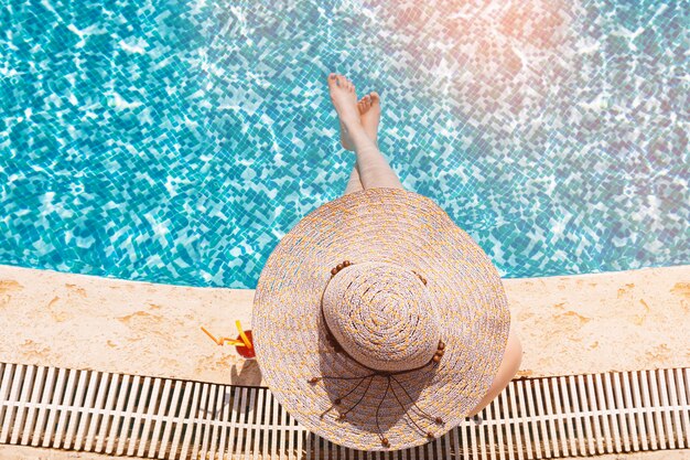 Niña con sombrero de sol emplazamiento junto a la piscina con cóctel