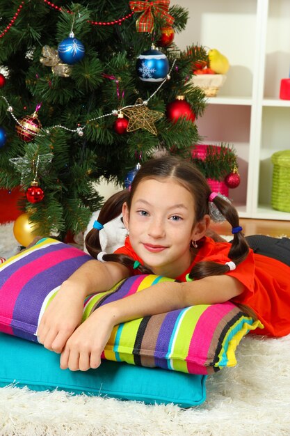 Niña soñando cerca del árbol de navidad