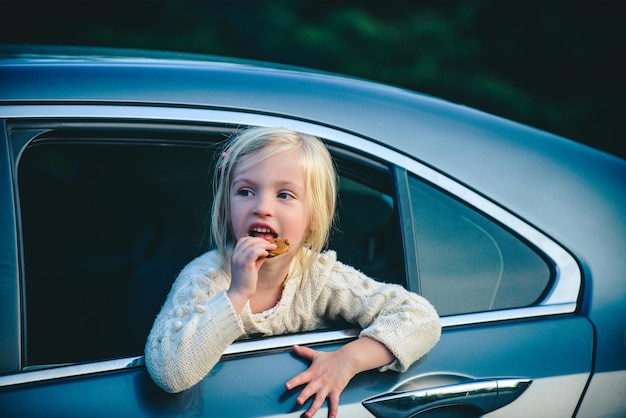 Niña soñando mirando desde la ventana del automóvil Retrato de niña pequeña sentada en el automóvil Niña linda sonriendo y divirtiéndose para viajar en automóvil