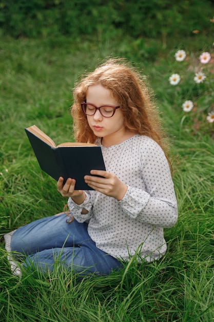 Niña soñando o leyendo un libro al aire libre. Concepto de educación