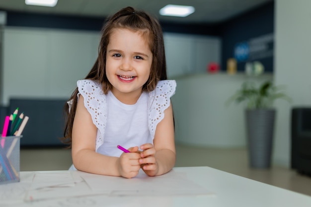 Una niña sonríe mientras dibuja en un papel