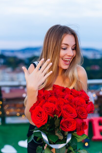 Foto la niña sonríe y muestra un anillo en el dedo anular. mujer sostiene un ramo de flores