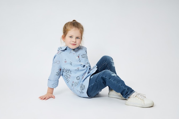 niña sonríe. niño en ropa de otoño posa en blanco