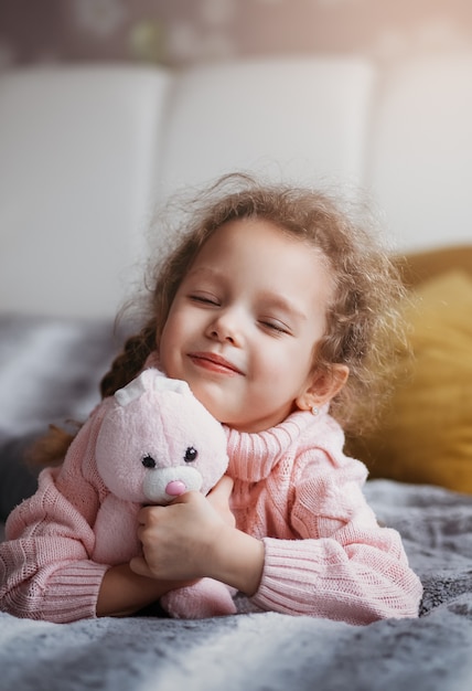 Niña sonríe con los ojos cerrados acostado en el sofá