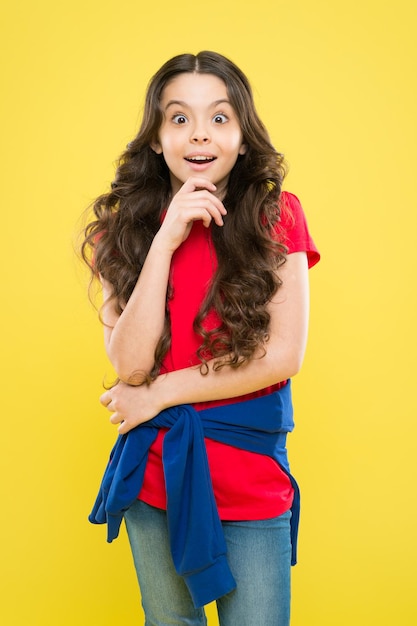 Niña sonriendo. felicidad infantil. salón de peluquería. cuidado de la piel y cabello natural. moda y belleza. niño sorprendido hipster. niña feliz con el pelo largo y rizado. infancia feliz. verano de la niñez.