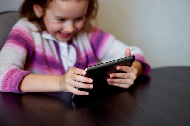 Niña sonriendo mientras se dedica a la tableta digital en el interior